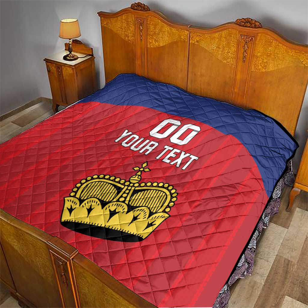 Custom football quilt on a bed, blue quilted backing with red center crown logo and 'YOUR TEXT'.