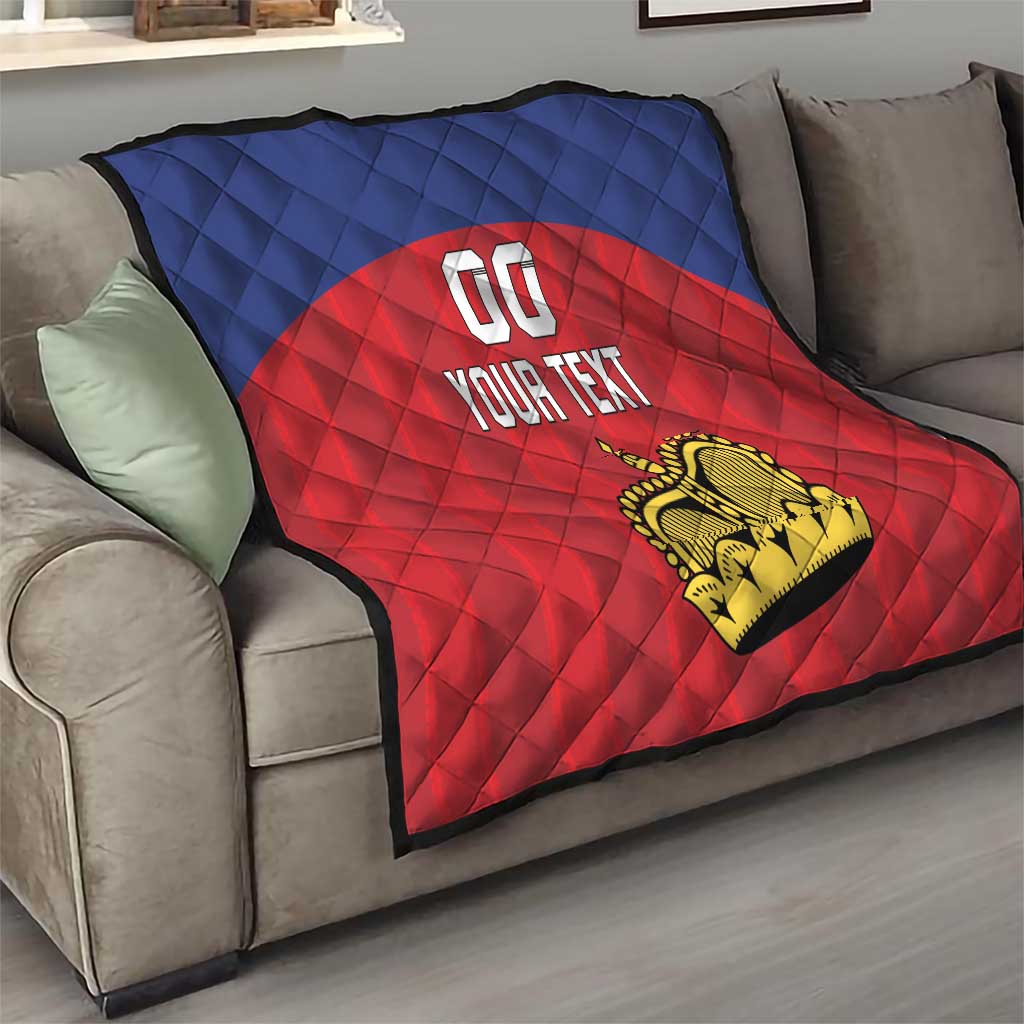 Custom football quilt draped on a couch, blue-and-red quilt pattern with crown logo and 'YOUR TEXT'.