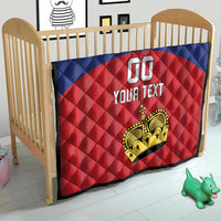 Custom football quilt on a child bed, blue and red diamond design with crown logo and 'YOUR TEXT'.