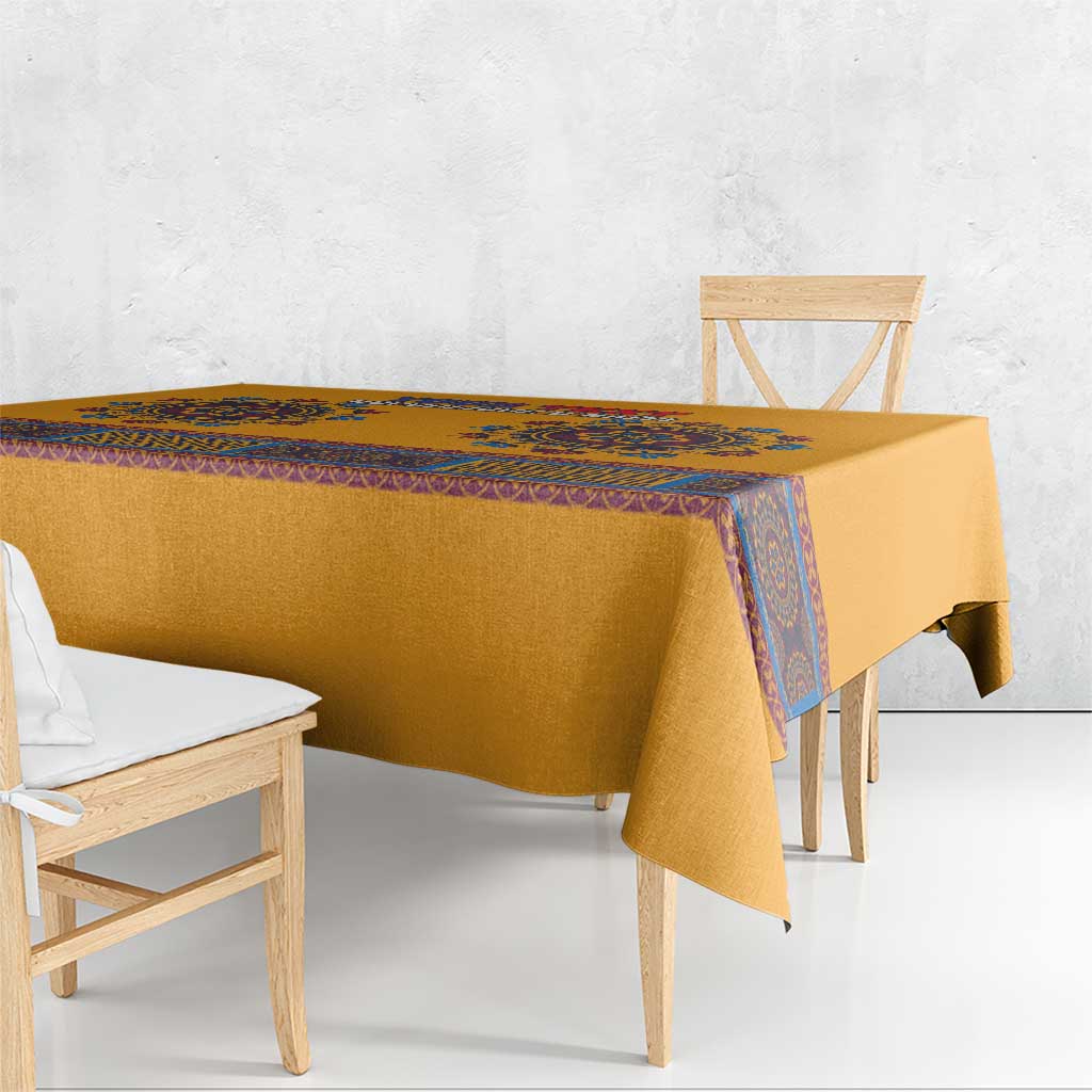 Yellow tablecloth with blue dashiki border draped over dining table edge
