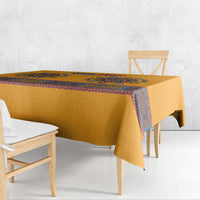 Yellow tablecloth with blue dashiki border draped over dining table edge