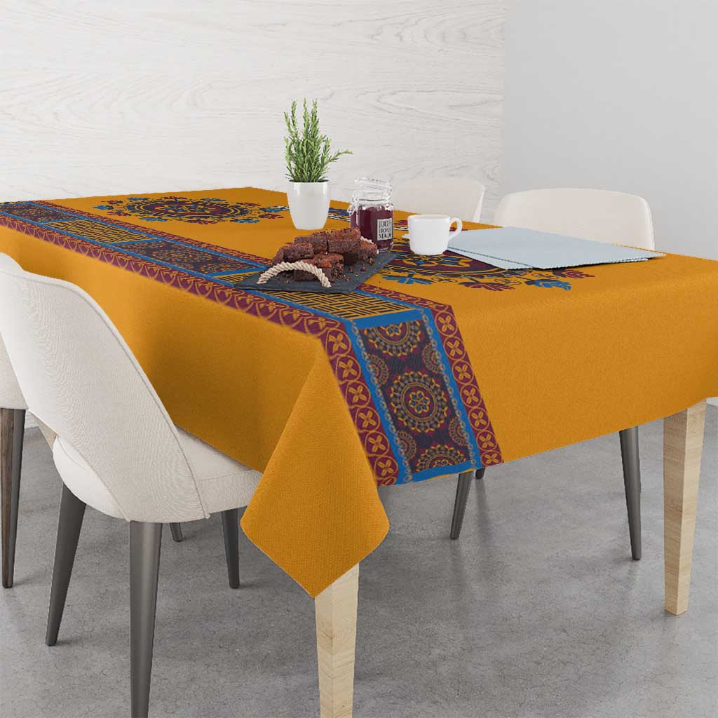 Yellow dashiki tablecloth with blue patterned border on dining table with matching items