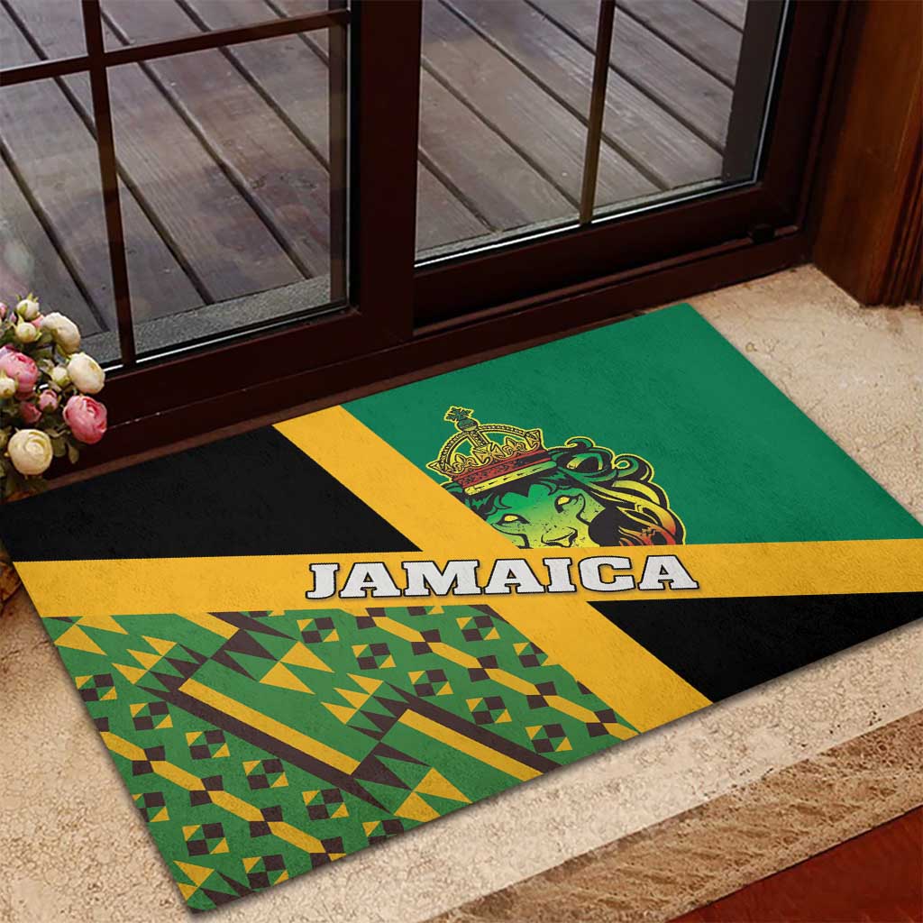 Green rubber doormat near doorway with Jamaica text, lion emblem, and geometric Kente pattern.