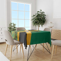 Green tablecloth with yellow and black geometric Kente pattern draped on dining table