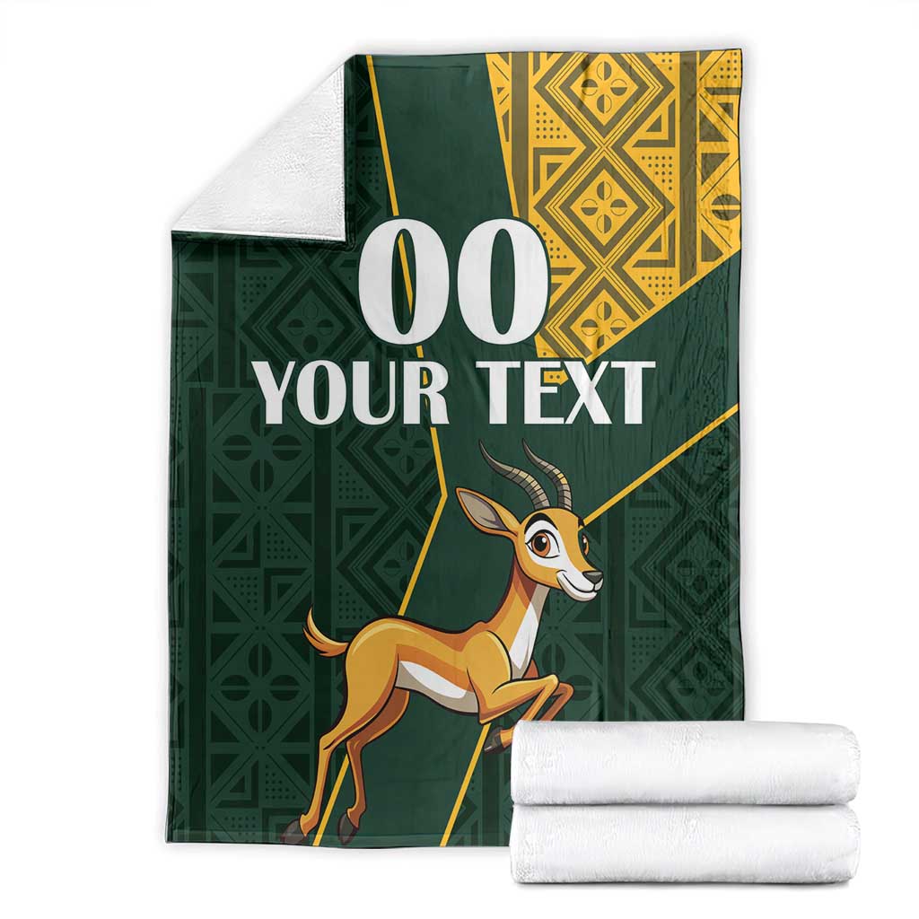 Green springbok blanket with yellow border, custom text, and stacked white towels