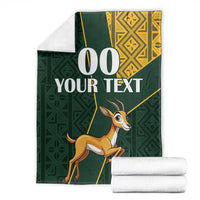 Green springbok blanket with yellow border, custom text, and stacked white towels