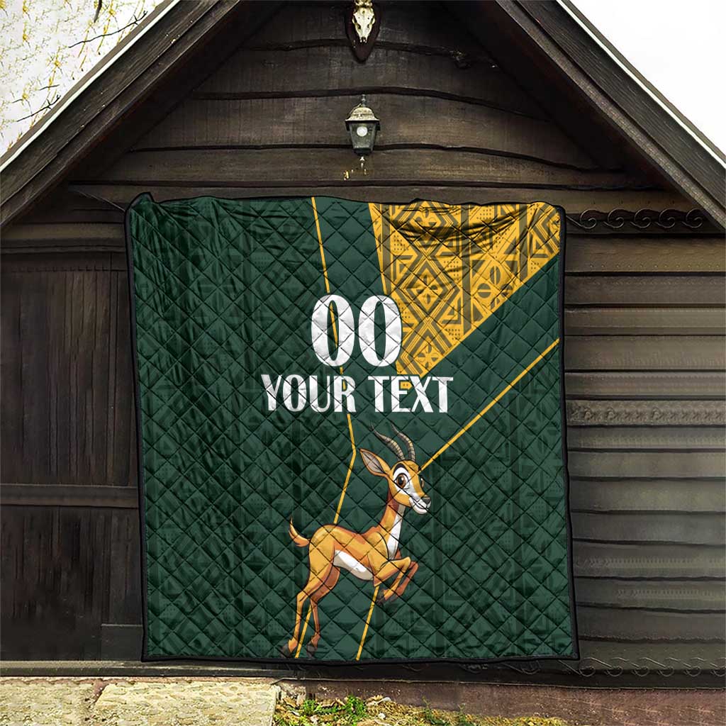 Dark green quilt hanging display with yellow Kente-style corner, springbok and “00 YOUR TEXT”