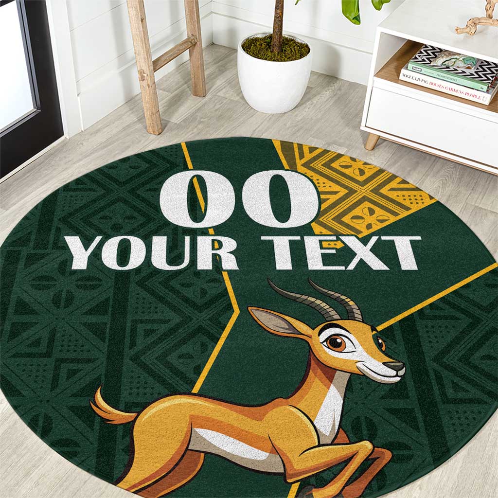 Round area rug in dark green with springbok graphic and yellow kente-style border
