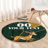 Round area rug in dark green with springbok artwork and “YOUR TEXT” lettering, yellow kente trim