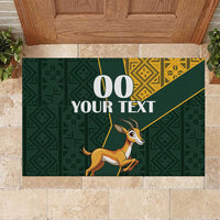 Green rubber doormat with custom text and jumping springbok graphic, yellow Kente pattern