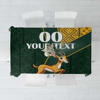 Green tablecloth with Kente-style yellow border and jumping springbok print