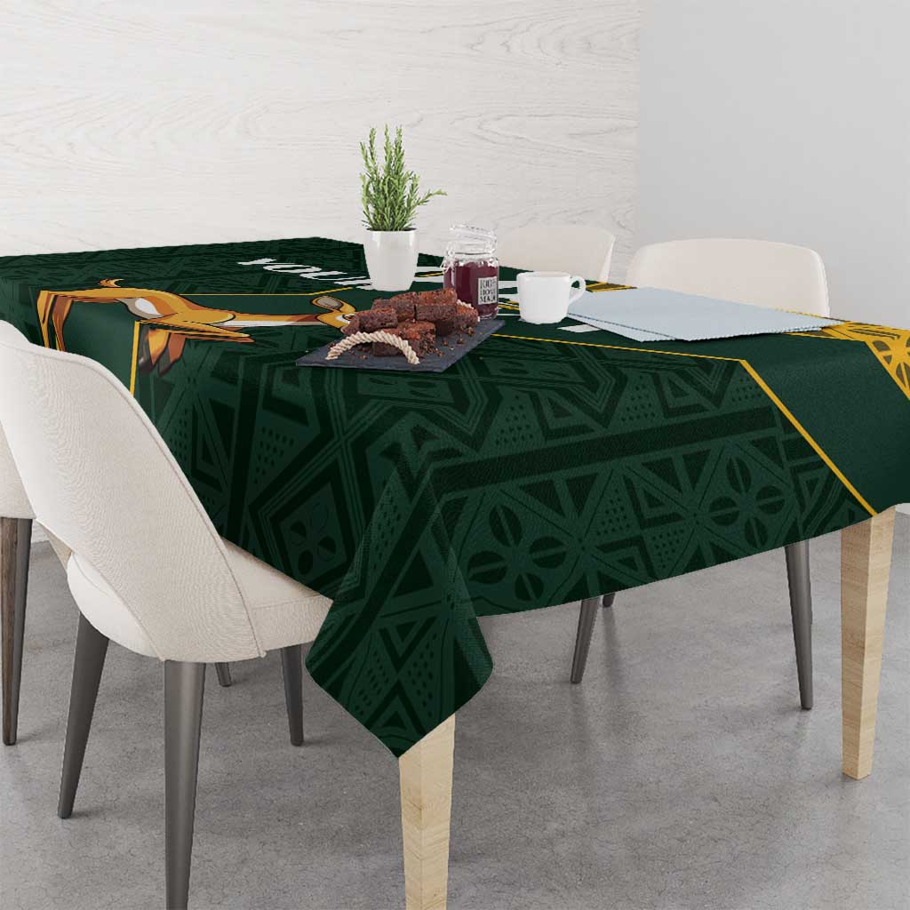 Green tablecloth with yellow border and springbok jumping motif across the center
