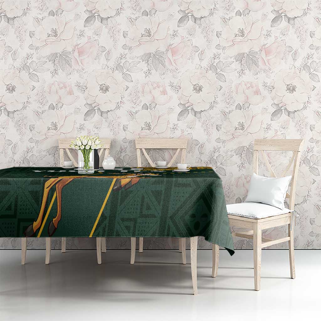 Green tablecloth with yellow patterned border and jumping springbok design