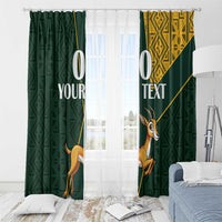 Green curtains with springbok artwork and yellow patterned panels, hanging over window