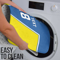 Blue and yellow bath mat being placed into a washing machine for cleaning