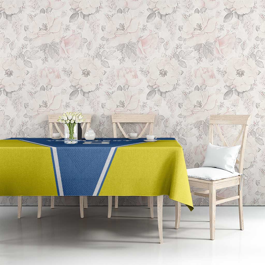 Blue and yellow tablecloth on dining table with chairs and floral centerpiece