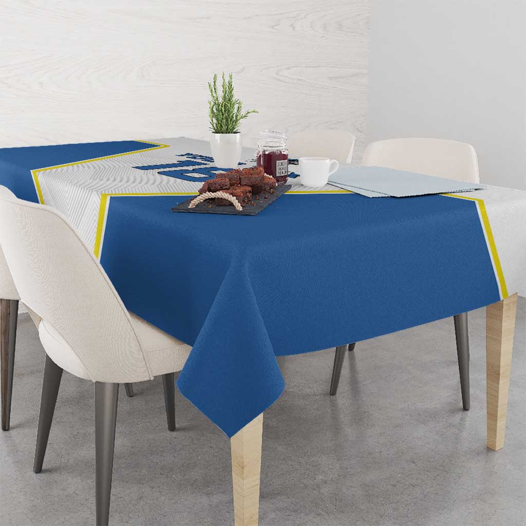 Blue and white tablecloth draped over dining table with yellow-trim border