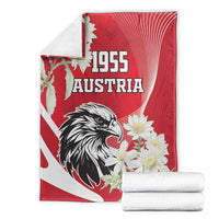 Folded red Austria blanket set with black eagle, “1955” text, and white flower accents