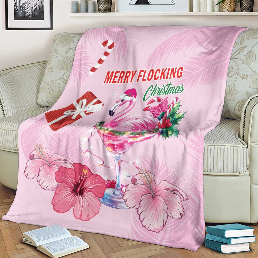 Pink flamingo Christmas blanket on sofa with candy cane, drink glass, and hibiscus flowers