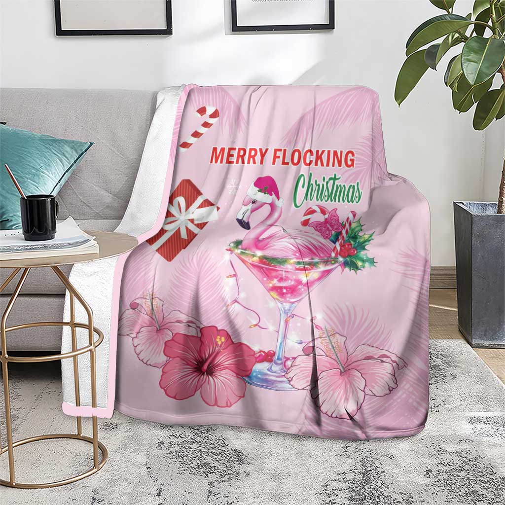 Pink Christmas blanket draped over sofa with flamingo, martini glass, and hibiscus prints