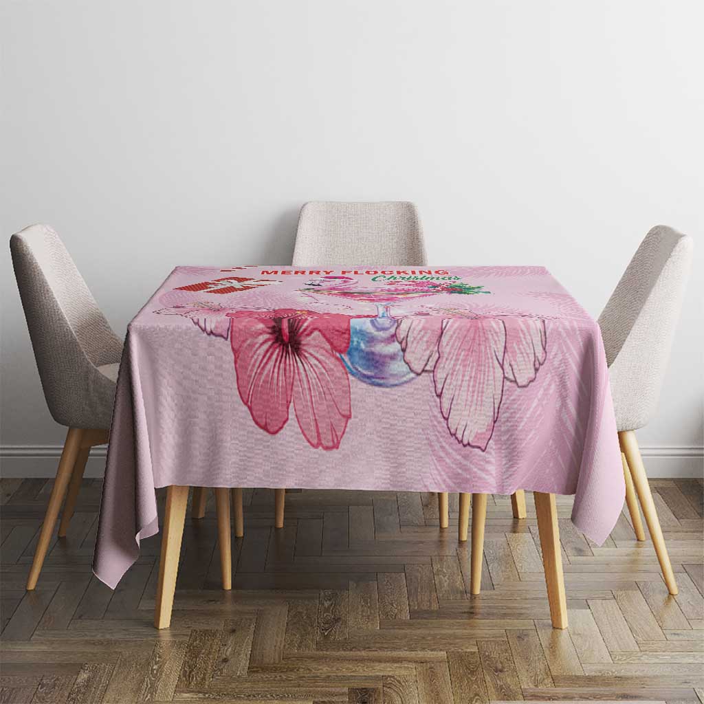 Pink Christmas tablecloth with floral artwork and red text, on dining table with chairs