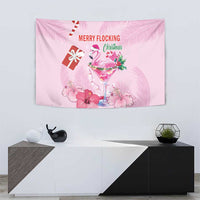 Pink flamingo Christmas tapestry with tropical leaves, flowers, drink glass, and 'Merry Flocking'