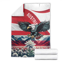Folded black eagle and Austria flag blanket with mountains, flower, and red-white stripes