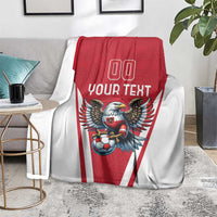 Red and white football blanket draped on sofa, eagle mascot and soccer ball with 'YOUR TEXT'.