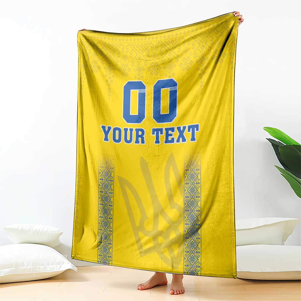 Yellow blanket draped with blue “00” and “YOUR TEXT” text and patterned trim