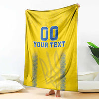Yellow blanket draped with blue “00” and “YOUR TEXT” text and patterned trim