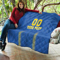Blue quilt blanket draped over couch, diamond quilting with yellow "00" and "YOUR TEXT"
