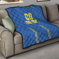 Blue quilt blanket on sofa, diamond stitching with yellow "00" and "YOUR TEXT" centered