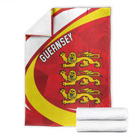 Red and yellow Guernsey crest blanket with lion emblem, neatly stacked with towels
