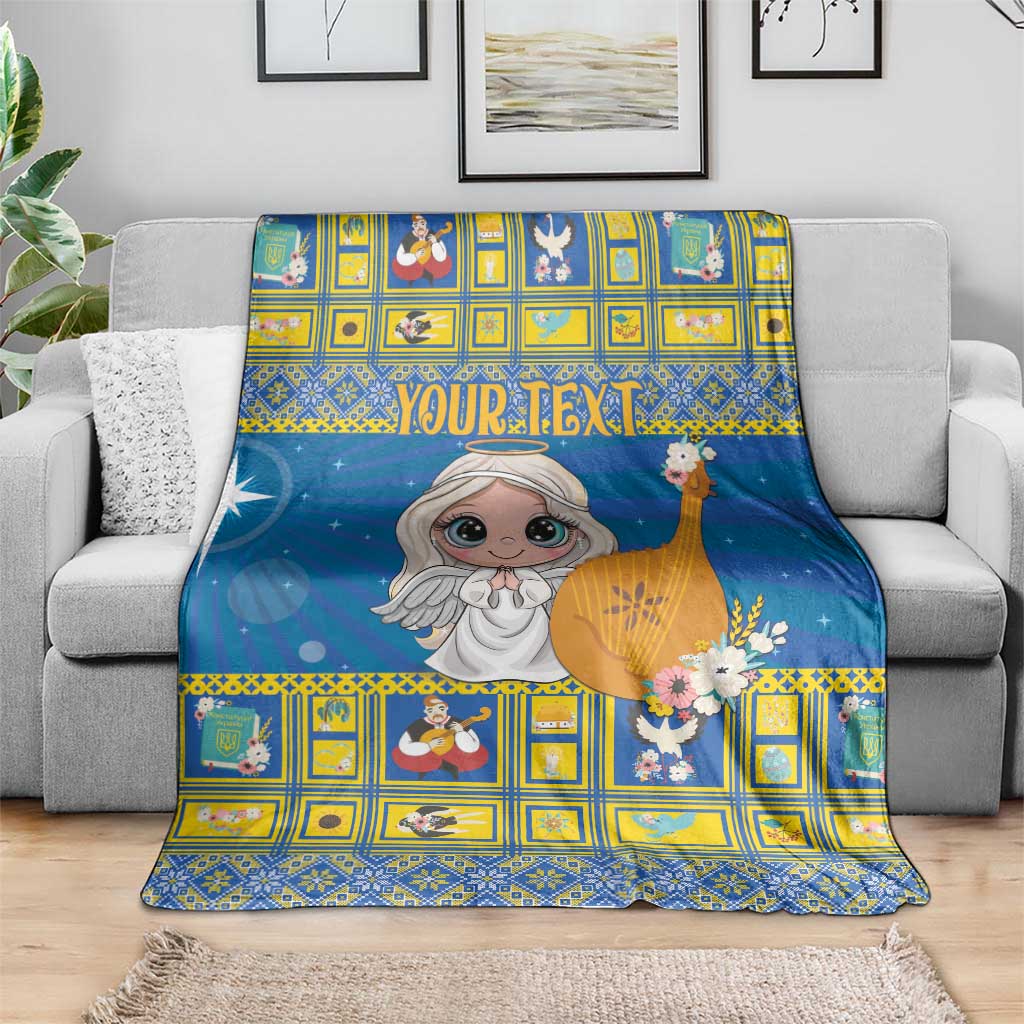Blue Christmas blanket with angel graphic and yellow geometric border, over sofa arm
