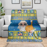 Blue Christmas blanket with angel graphic and yellow geometric border, over sofa arm