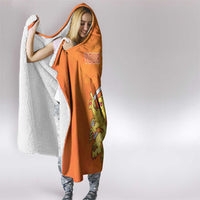 Orange hooded blanket with white fleece edge, side view while being worn