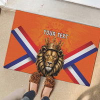 Orange rubber doormat showing crowned lion head, Dutch flag stripes, and 'YOUR TEXT'.