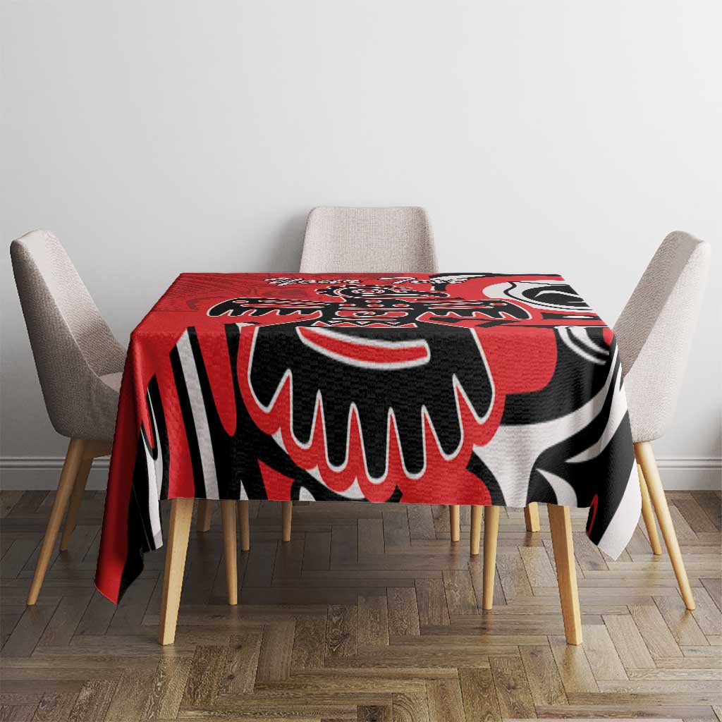 Red tablecloth with black and white eagle-style print covering the dining table