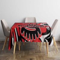 Red tablecloth with black and white eagle-style print covering the dining table