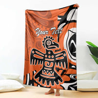 Personalized orange Haida eagle blanket draped on couch, showing “Your Text” and eagle design