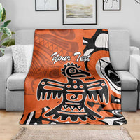 Personalized orange Haida eagle blanket on gray sofa, featuring “Your Text” and eagle motif