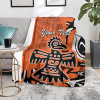 Personalized orange Haida eagle blanket spread on gray couch seat, showing “Your Text” and eagle