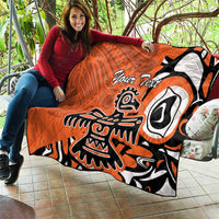 Orange quilt with Haida-style eagle graphic and “Your Text”, held over a couch