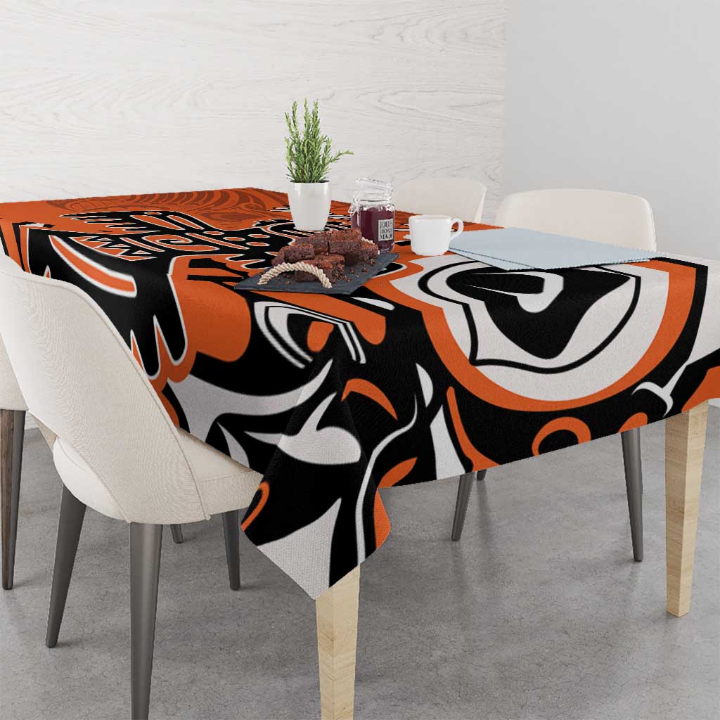 Orange, black, and white patterned tablecloth on dining table with chairs