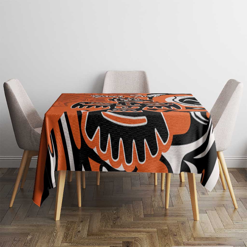 Orange, black, and white patterned tablecloth on square dining table