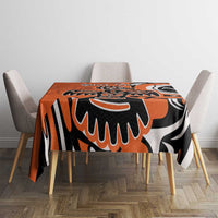 Orange, black, and white patterned tablecloth on square dining table