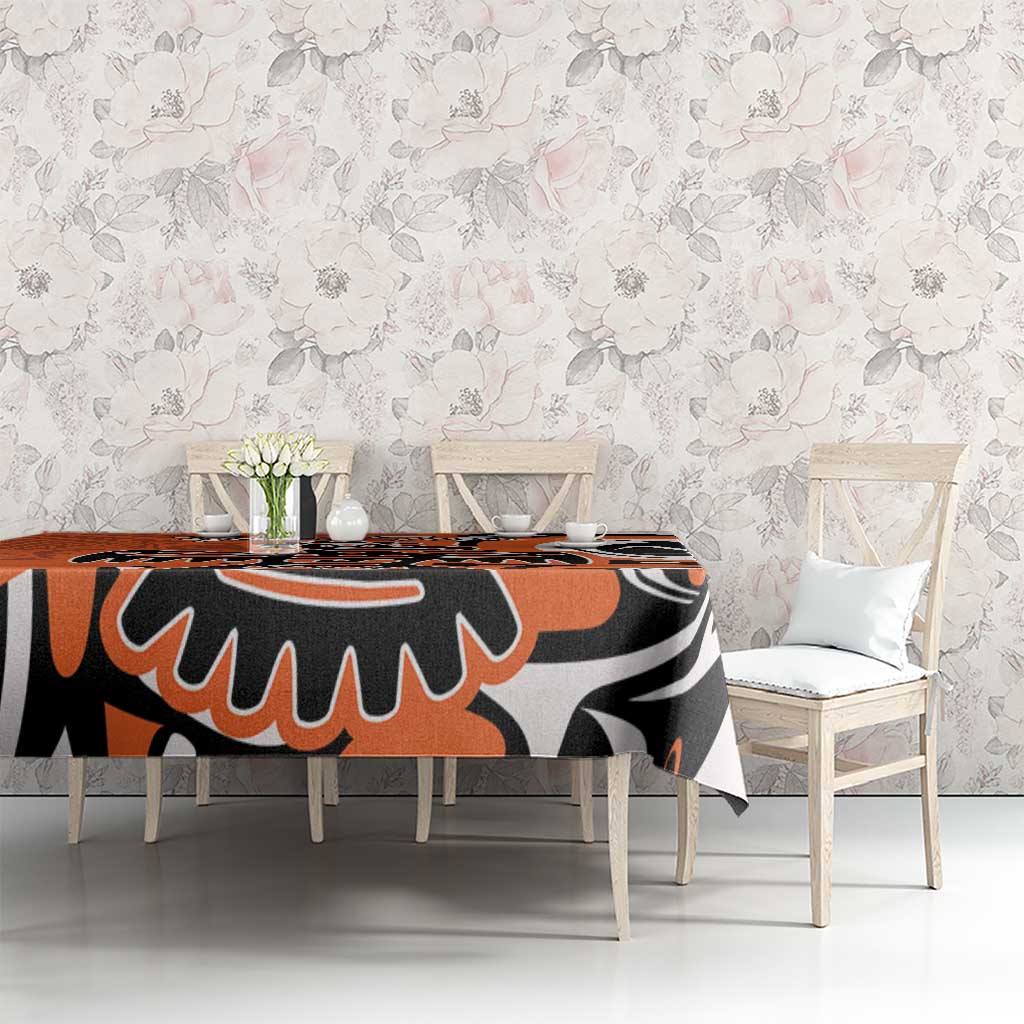 Orange, black, and white patterned tablecloth covering dining table