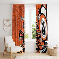 Orange curtains with black-and-white eagle print, hanging over a sunny window