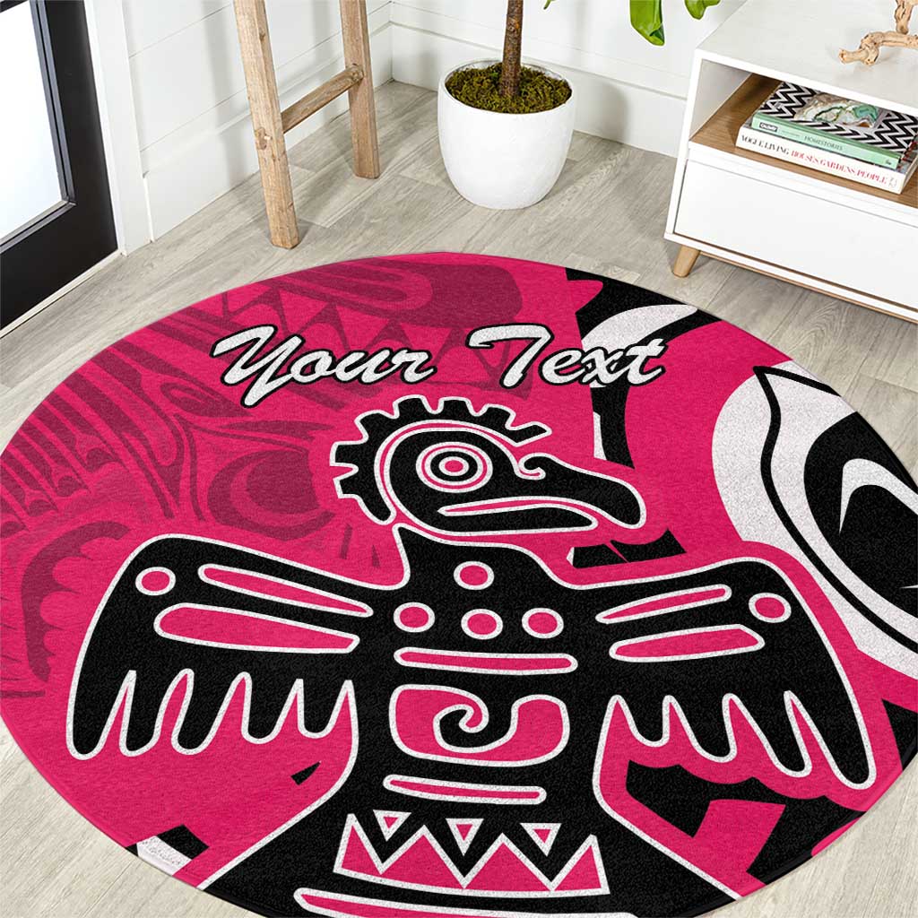 Pink round area rug with central Haida-style eagle face and 'Your Text' script