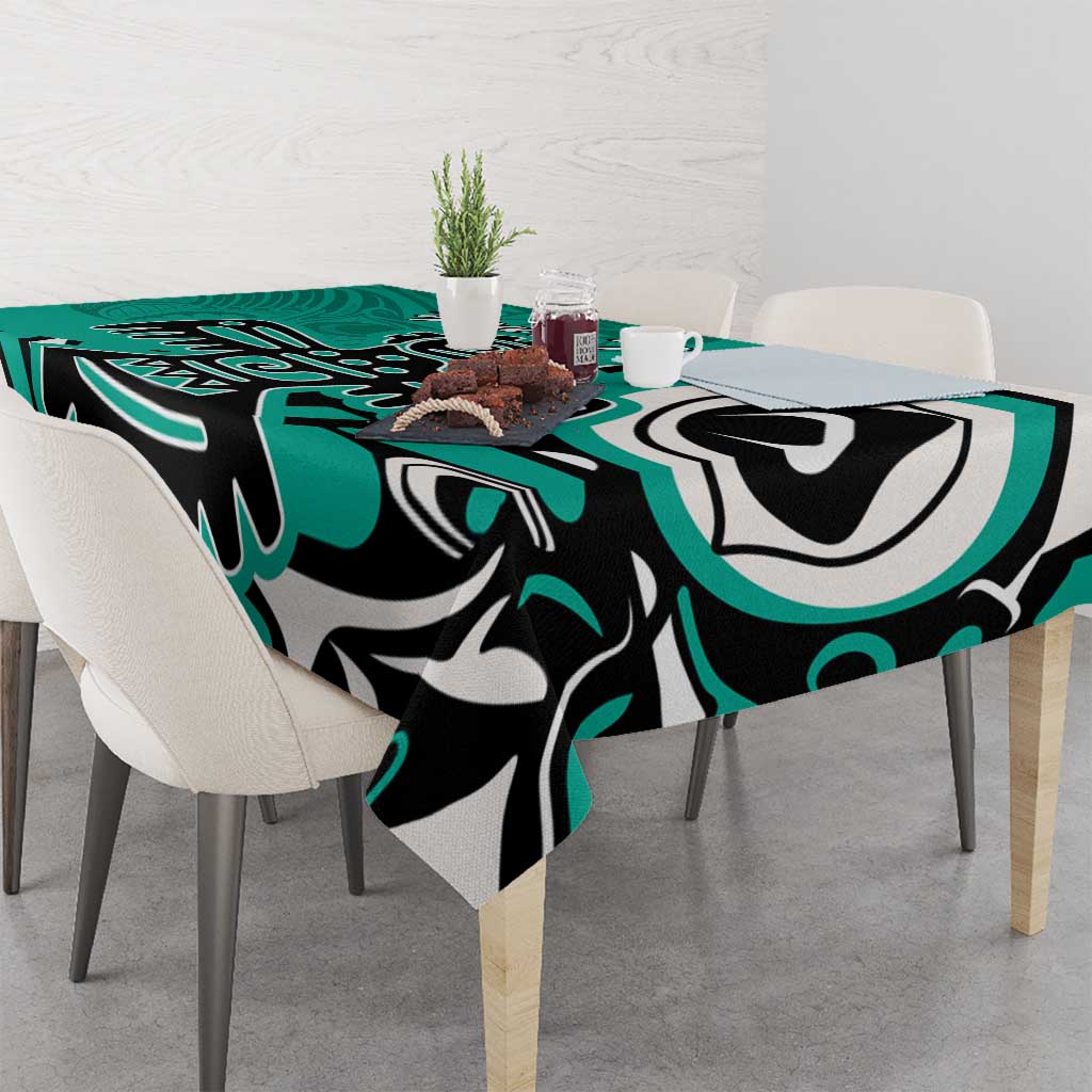 Turquoise tablecloth with black and white eagle artwork, on dining table with chairs